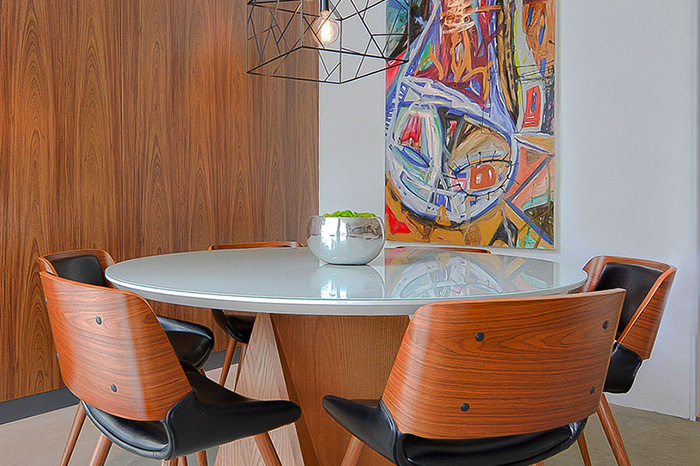 Mesa de jantar redonda, cadeiras laminadas e esfotadas e pendente aramado.